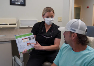 A dental assistant shows a patient important information about tooth health via a spiral booklet at Rocky Creek Dental Care