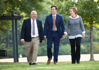 The three doctors of Rocky Creek Dental Care walking and smiling together as they walk along in a grassy field